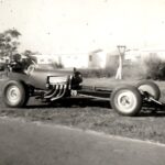 An old black and white photo of a drag racing car.