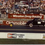 A drag car showcasing its speed and power in front of a cheering crowd.