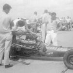 A group of men standing around a drag race car.
