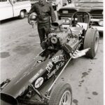 A man standing next to a drag racing car.
