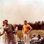A group of men standing next to a drag racing car.