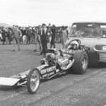 A man participating in drag racing, driving a high-powered drag car.