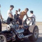 A group of men standing around a Drag Racing car.