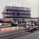 Two drag racers compete on a track with a crowd of enthusiastic spectators.