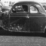 A vintage black and white photo of an old car showcasing its sleek design.