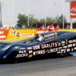 A man participating in drag racing, driving a mesmerizing drag car with smoke billowing out of it.