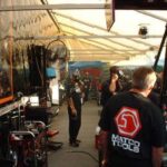 A group of people standing around in a tent at a Drag Racing event.