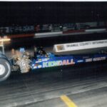 A blue dragster speeding through the darkness in a thrilling display of drag racing prowess.
