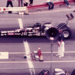 An old photo of a drag racer in front of a crowd at a Drag Racing event.