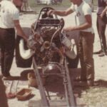 A group of men working on the engine of a drag racing car.