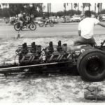 An old photo capturing a man in a powerful drag car during an exhilarating drag racing event.
