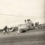 An old photo of a man participating in drag racing on a motorcycle track.