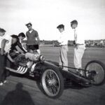A group of men standing around a drag racing car.