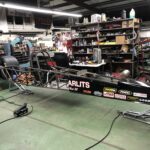 A drag racing car is being meticulously worked on in a garage.