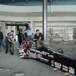 A group of people standing around a Drag Racing race car.