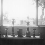 Drag racing trophies on a table in front of a window.