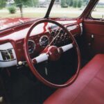 The interior of a red car with leather seats and steering wheel, perfect for drag racing enthusiasts.