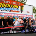 A group of people posing with a drag racing car.