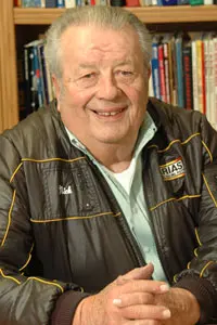 Smiling elderly man in a jacket.