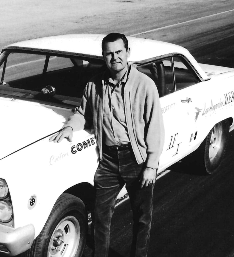 Man leaning on a vintage racing car.