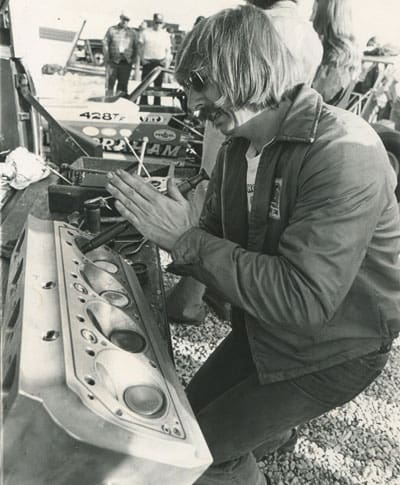 Man working on a racing engine component.