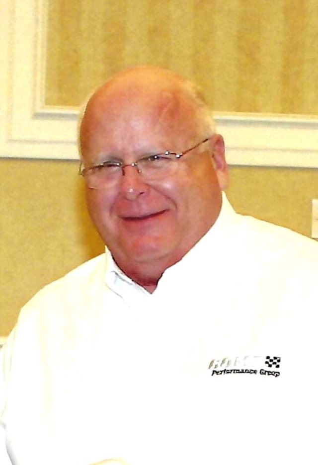 Smiling man in white shirt, casual setting.