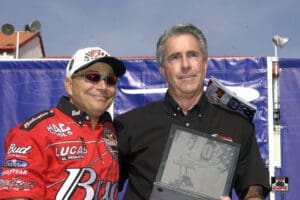 Two men posing with a racing award.