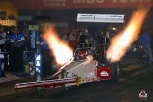 Dragster car with flames racing at night.