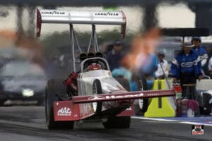 Dragster launching with flames on track.