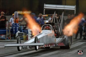 Dragster accelerating with flames on racetrack.