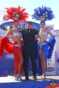 Racing driver with two showgirls in costumes.