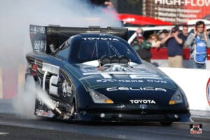 Black drag racing car at starting line.