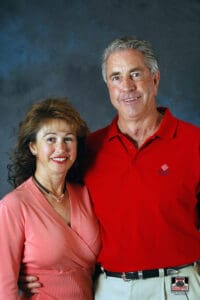 Smiling couple posing against dark background.