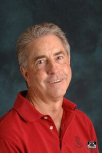 Man smiling in a red polo shirt.