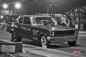 Vintage drag racing car at night event.