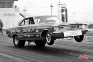 Vintage drag racing car lifting front wheels.