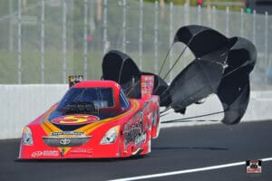 Red drag racing car with parachutes deployed.