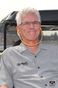 Smiling man with glasses and gray hair.