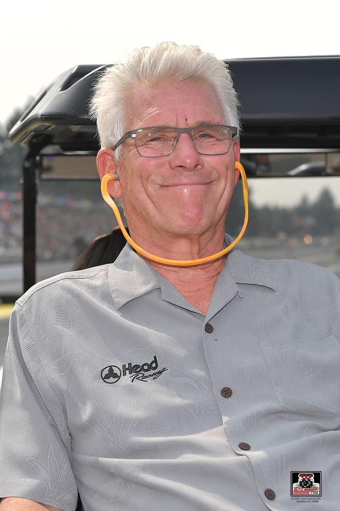 Smiling man with glasses and gray hair.