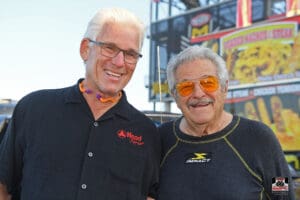 Two smiling men in casual clothing outdoors.