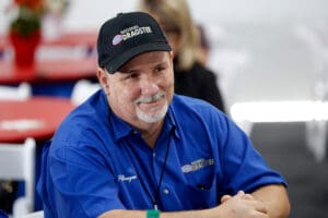 Man in blue shirt and cap smiling.