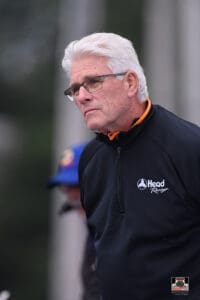 Older man in black jacket outdoors.