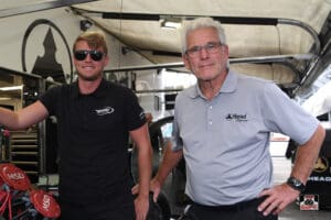 Two men standing in a racing garage.
