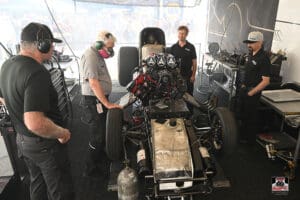 Crew working on drag racing car engine.