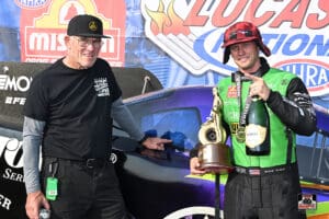 Two men celebrating with trophy and champagne.