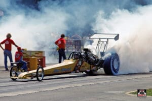 Dragster burnout with smoke on racetrack.