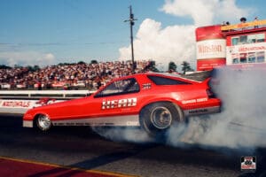 Red drag racing car with smoky burnout.