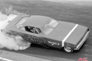 Red Dodge Charger drag racing with smoke.