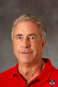 Man in red shirt, neutral expression.