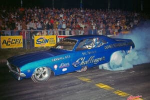 Blue drag car racing with crowd watching.